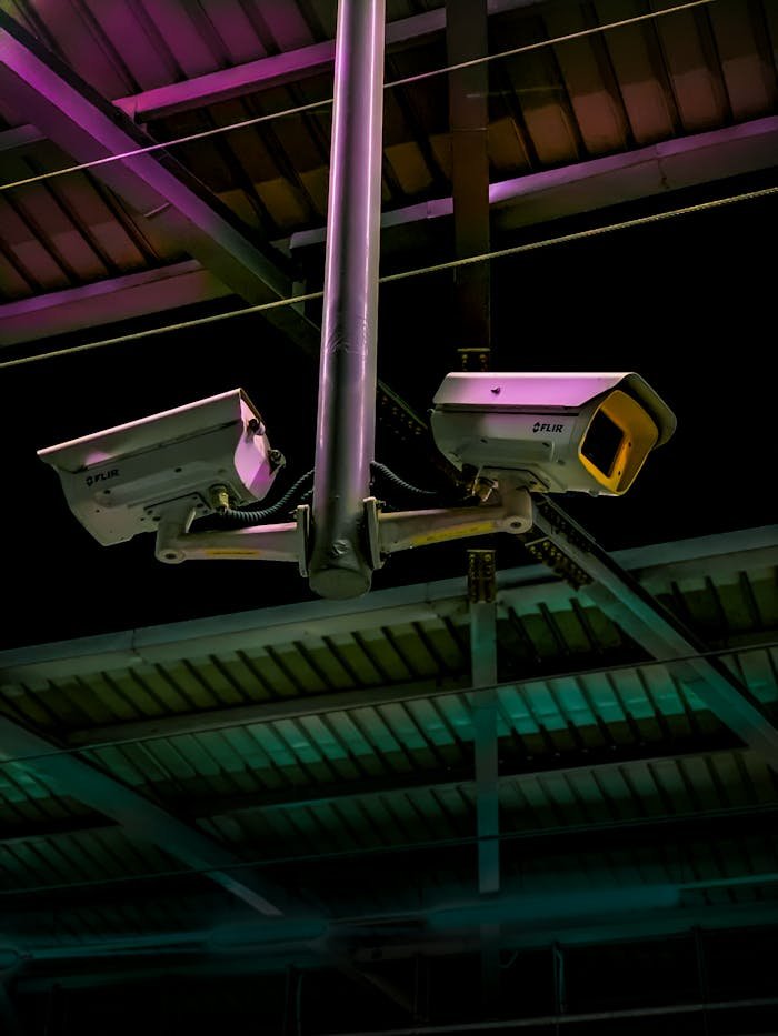 Pair of security cameras installed in an industrial setting with vibrant lighting.