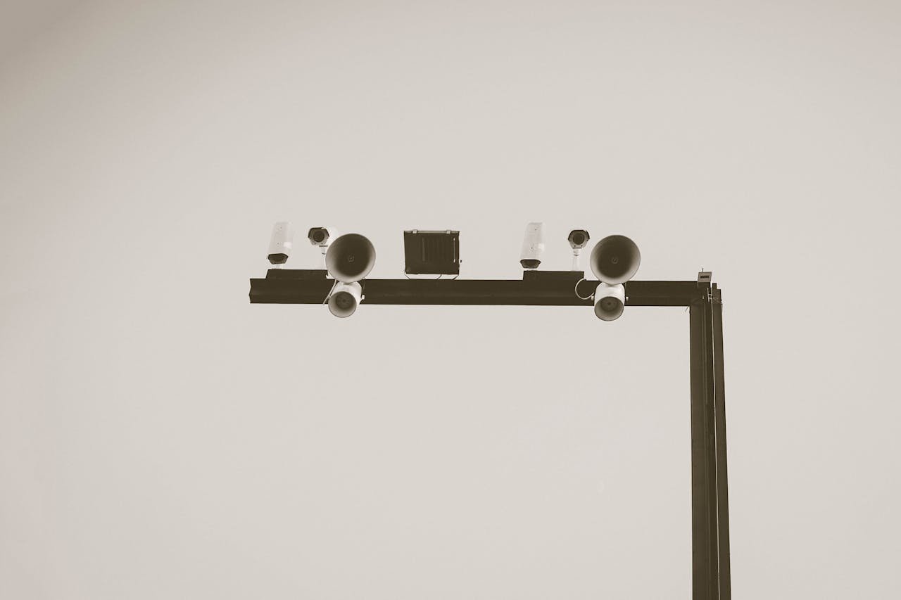 Monochrome image of CCTV cameras and speakers on an outdoor metal frame in Barcelona.